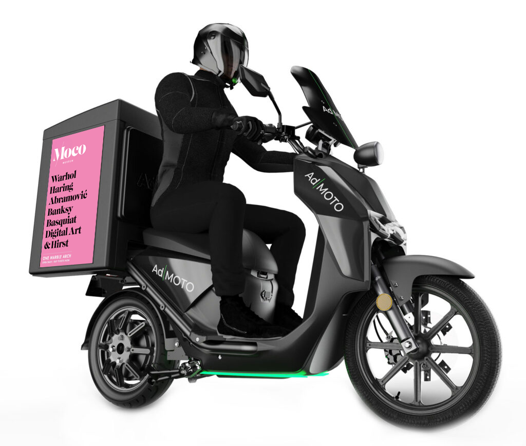 Sideways image of an Ad|MOTO rider sat on a motorbike with an advertisement at the back